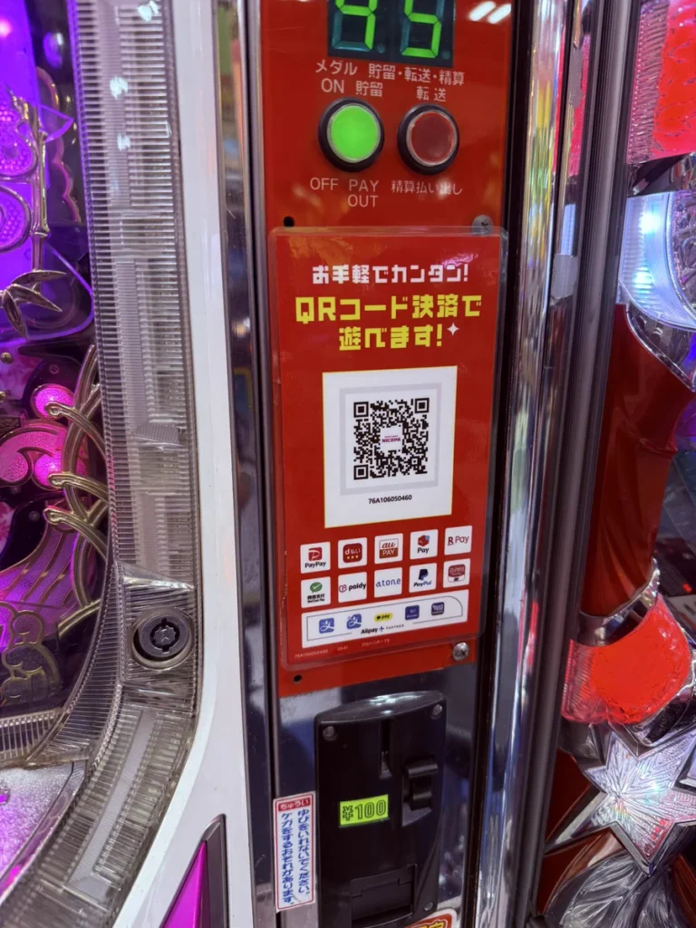 ゲームセンターのパチンコ台に設置されたQRコード決済用の案内と読み取り機